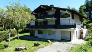 Kaksikerroksinen, moderni talo, jossa on parveke, autotalli ja hyvin hoidettu puutarha.