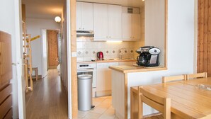 A compact kitchen with white cabinets, a coffee maker, and a trash can. - Tignes Apartment, 2 rooms, 500m from slopes (Tignes)
