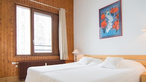 A double bed with white bedding in a room with wooden walls and a large window. - Tignes Apartment, 2 rooms, 500m from slopes (Tignes)