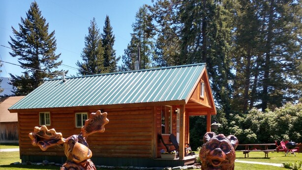 Una cabaña de madera con techo verde y un letrero que dice 'Welcome to Kozy Cabins'.