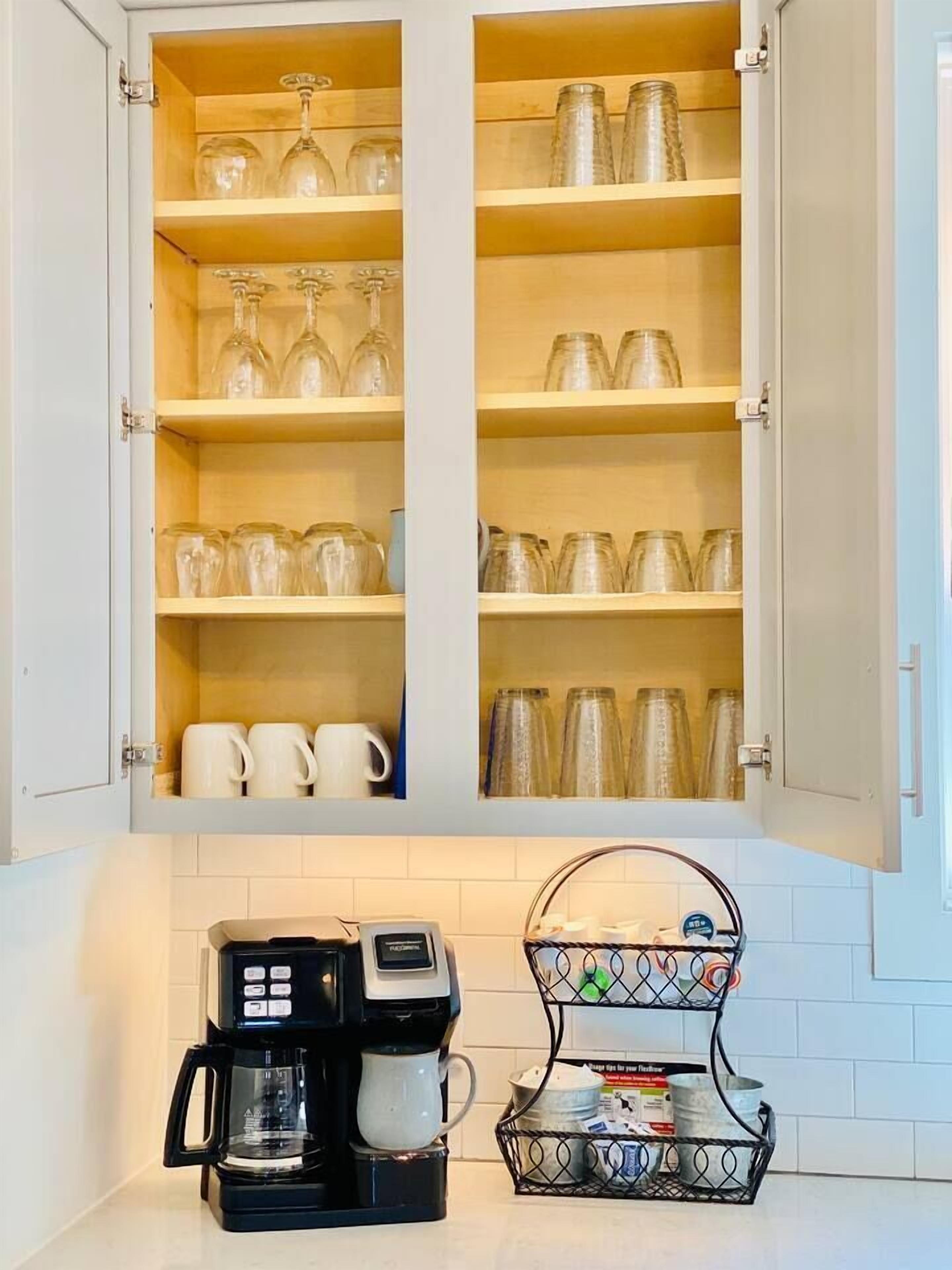 Une cuisine équipée d’une machine à café et d’un panier rempli de divers objets posé sur le comptoir.