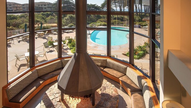 A stone fireplace with a view of a pool and outdoor seating area.