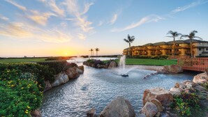 A resort with a water feature, palm trees, and a building with balconies.