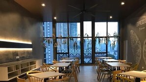 En restaurang med många bord och stolar, stora fönster med utsikt över staden och en modern inredning.