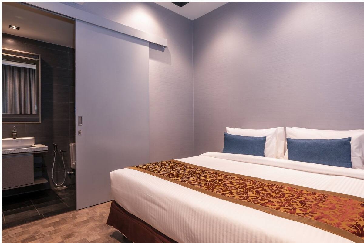 A hotel room with a bed, a bathroom, and a mirror.