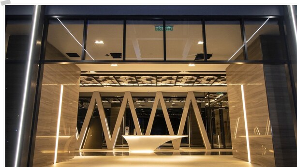 En modern hotellentrén med en geometrisk ljusinstallation och en central receptionsdisk.