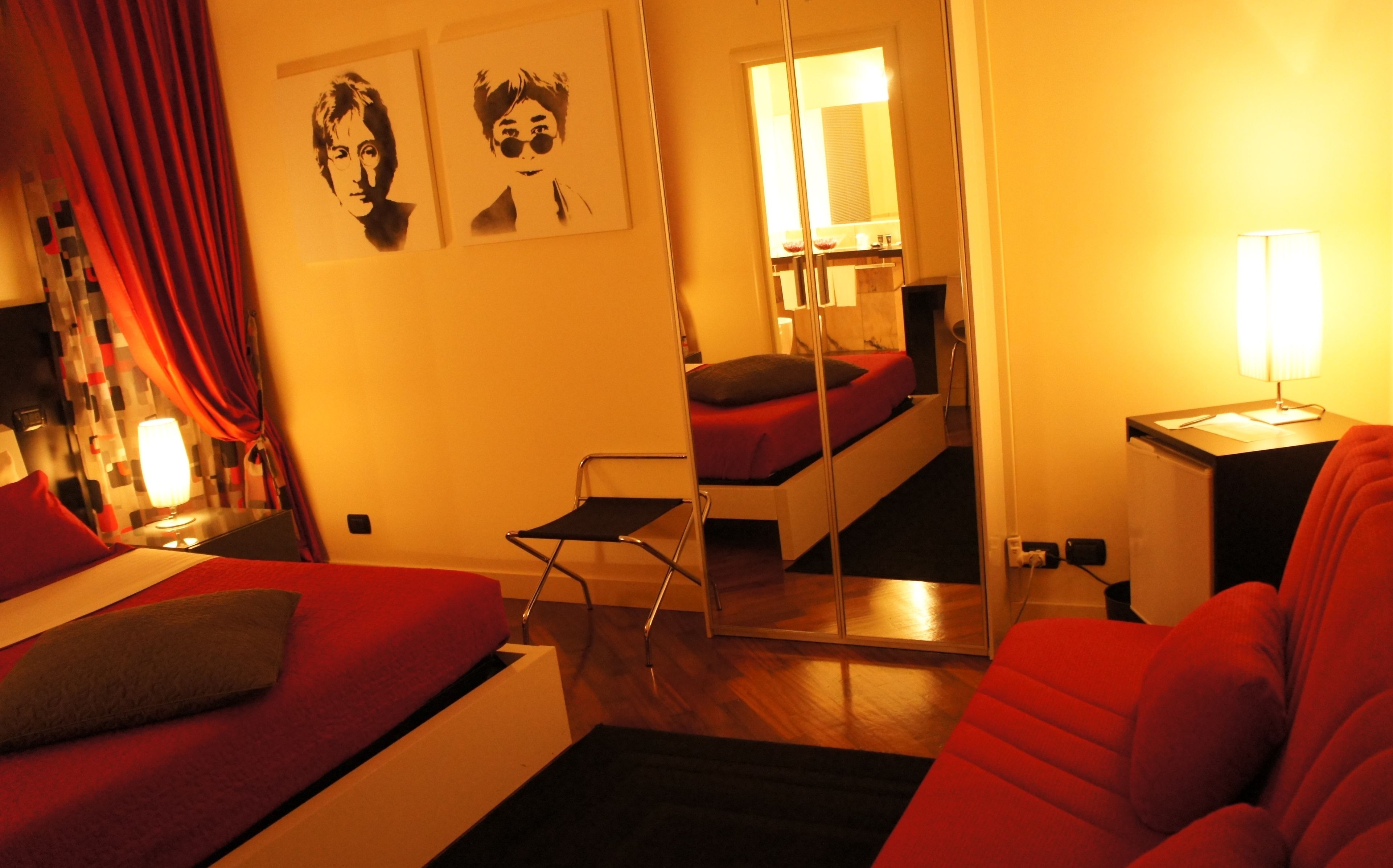 Una camera d'albergo compatta con un letto, una piccola scrivania, una sedia e uno specchio.