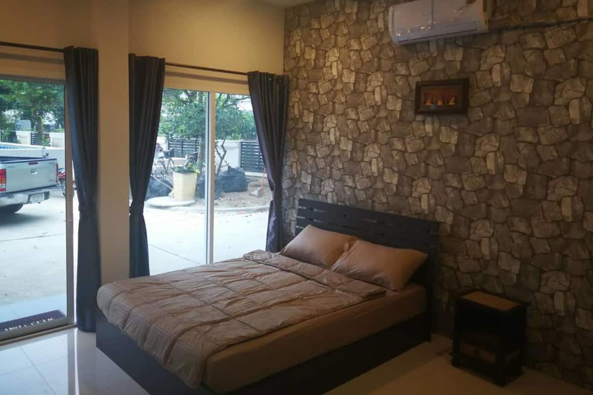 A bedroom with a stone wall, a bed, and an air conditioning unit.