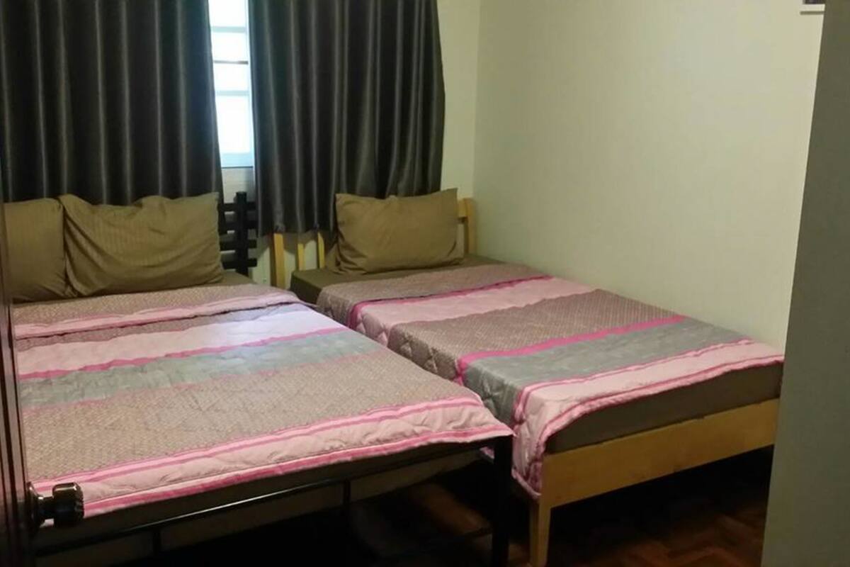 A room with two single beds, each with a pillow and a blanket.