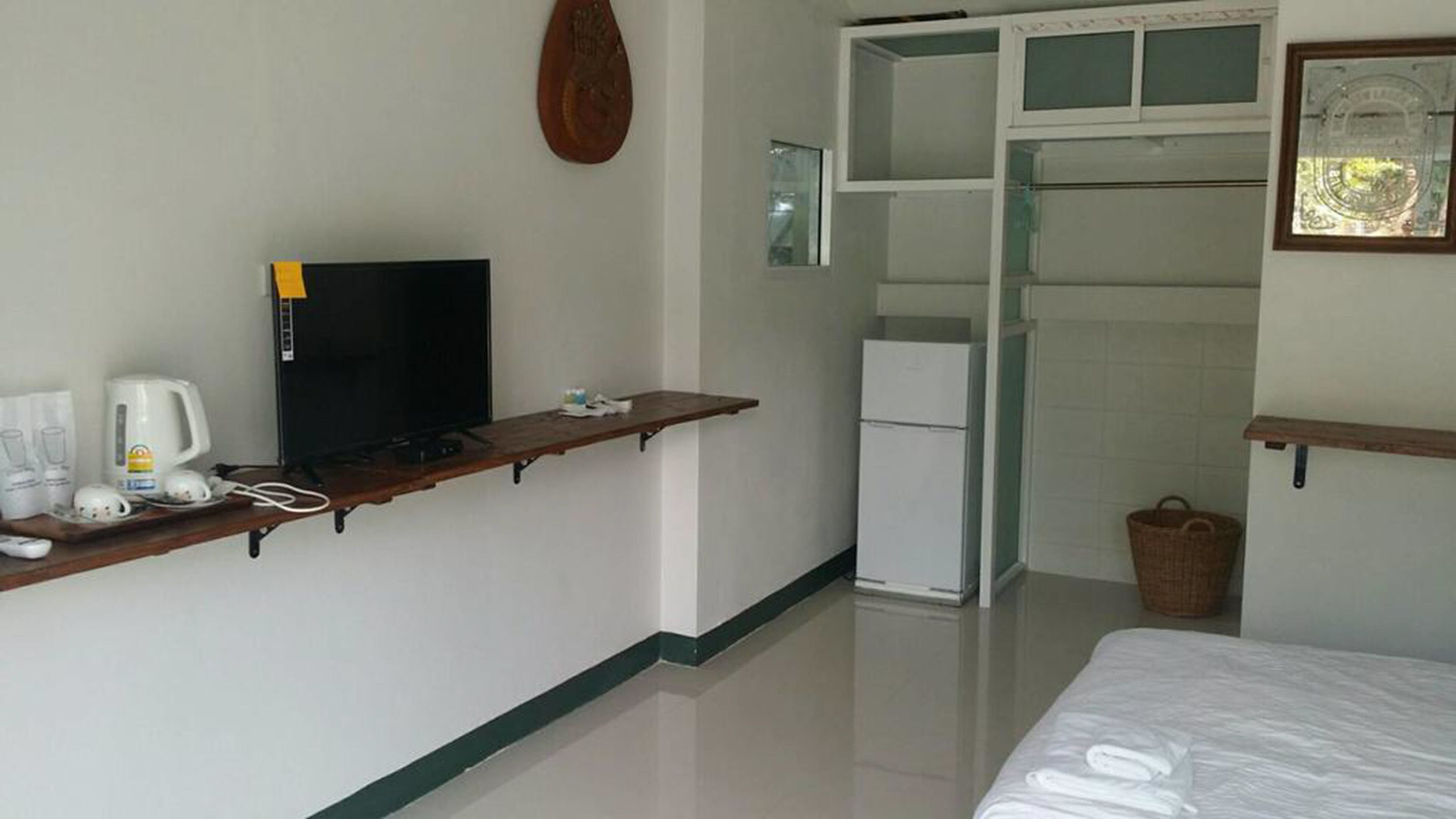 A hotel room with a bed, a TV, a coffee maker, and a refrigerator.