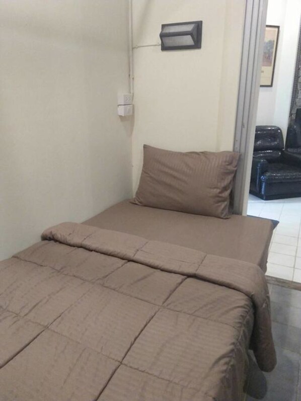 Una habitación pequeña y sencilla con cama, almohada y una silla.