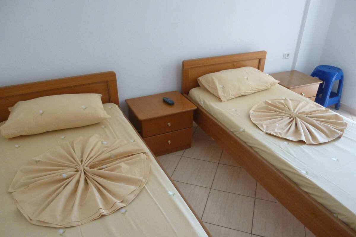 Two single beds with wooden headboards, beige bedding, and decorative pillows.