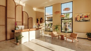 Un área de recepción con un escritorio de madera, separadores de mimbre y vistas al exterior a través de amplios ventanales.