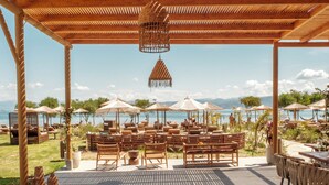 Un espace extérieur aménagé avec des meubles en bois et des parasols, offrant une vue sur une étendue d’eau.