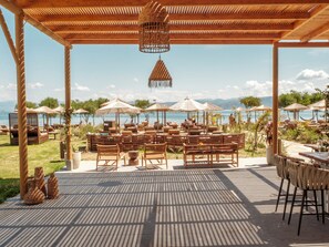 Un área de estar al aire libre con muebles de madera y sombrillas, con vista a una masa de agua.