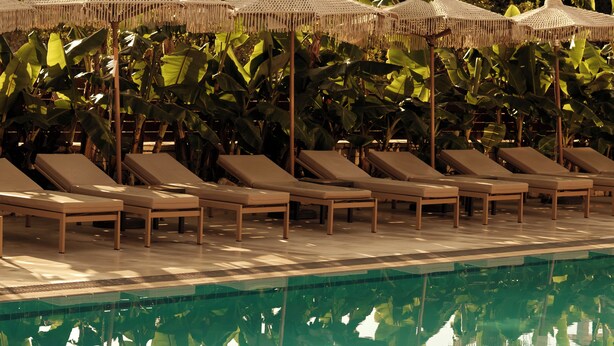 Un espace aménagé au bord de la piscine, avec des chaises longues et des parasols.