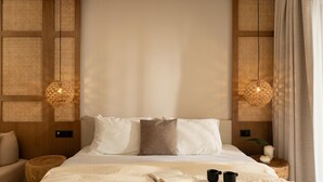 Un dormitorio ordenado con cama, mesitas de noche y una lámpara colgante.
