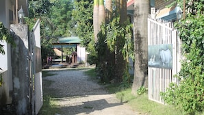 A gravel path leading to a gated entrance with a small structure in the background.