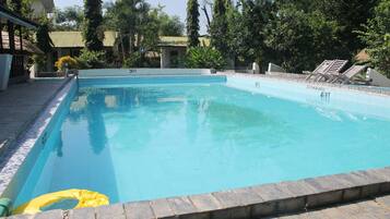 A rectangular swimming pool with a tiled edge, surrounded by a stone border.