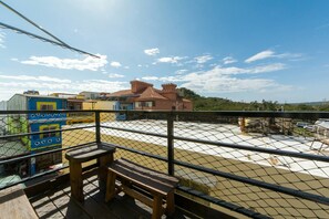 A balcony with a wooden bench, a chain-link fence, and colorful buildings in the background. - Kenting central point star Bay Hotel (Hengchun)