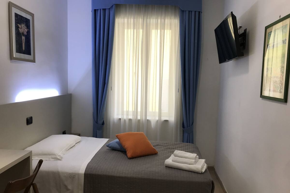 Une chambre d’hôtel avec un lit, un bureau et une chaise.