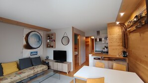 Uma sala moderna com sofá, televisão e área de jantar com mesa e cadeiras.