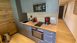 Uma cozinha compacta com armários cinzas, forno de aço inoxidável, cafeteira e pia.