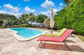 A swimming pool with a tiled deck, surrounded by greenery and a clear sky. - Homerez - Enchanting Villa with Private Pool in Eyragues (Eyragues)