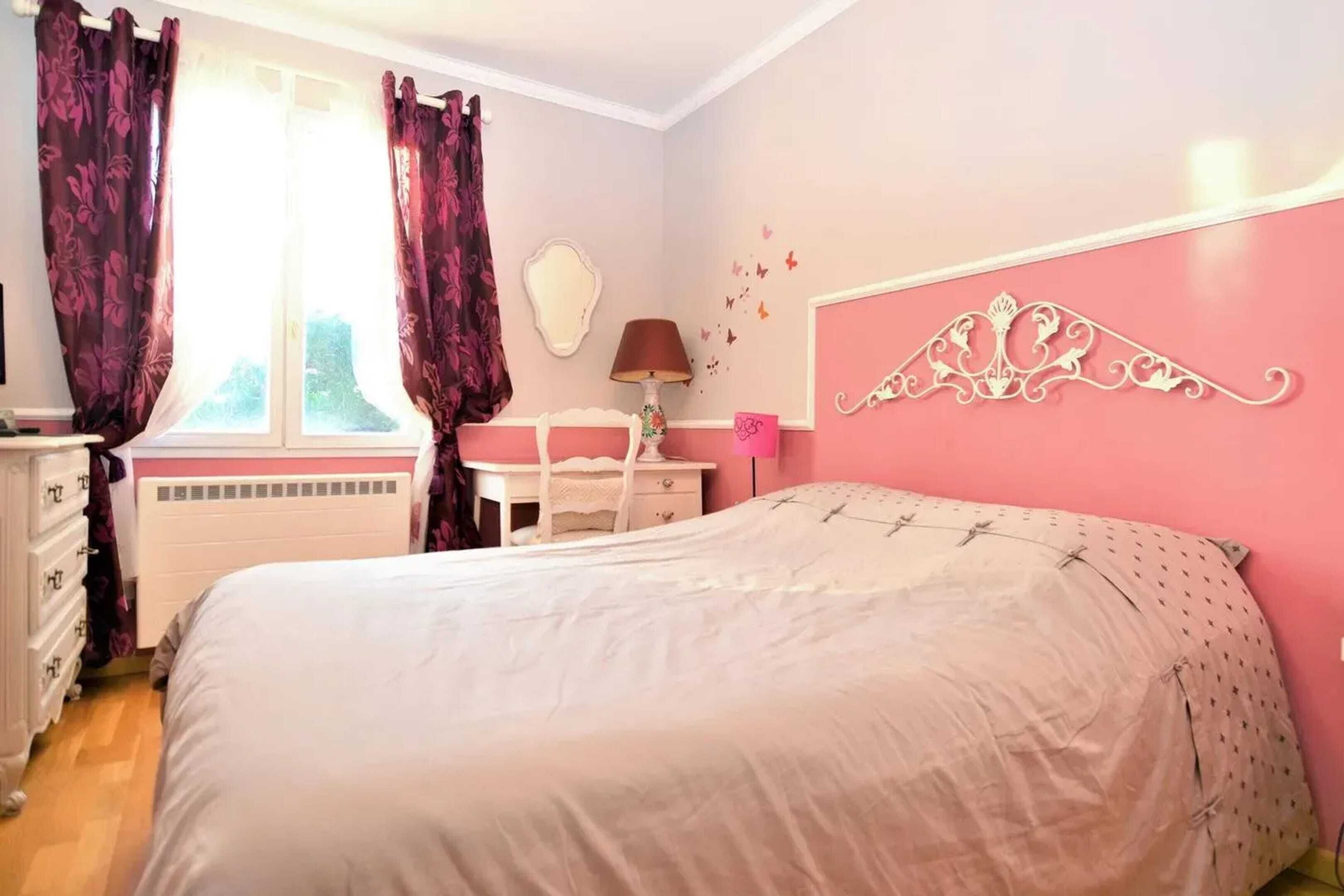 A bedroom with a bed, a dresser, a desk, and a window with curtains.