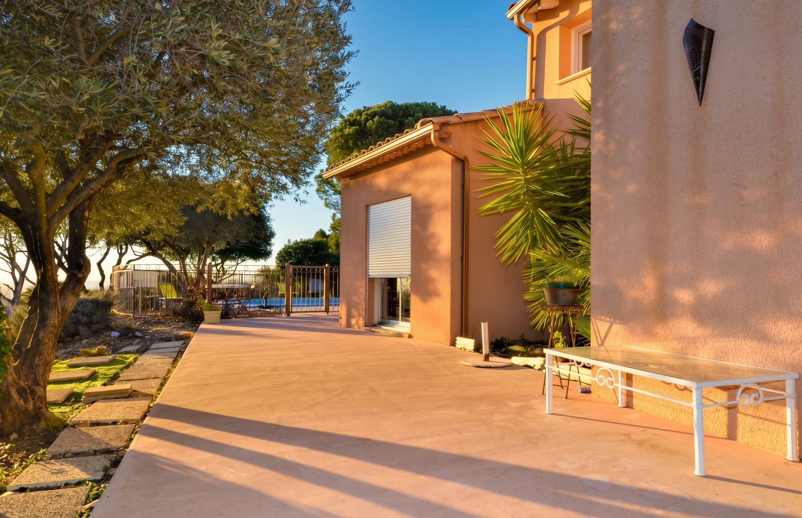 A building with a closed garage door, a paved walkway, and a bench.
