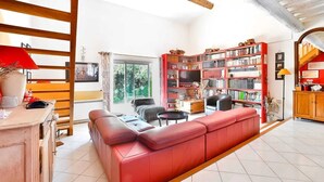 Un salón espacioso con un sofá rojo, una estantería de madera y un televisor.