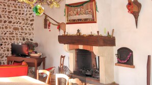 A cozy room with a fireplace, stone wall, wooden furniture, and a painting of 'The Last Supper'. - Homerez - House in Bernac-Dessus (Bernac-Dessus)