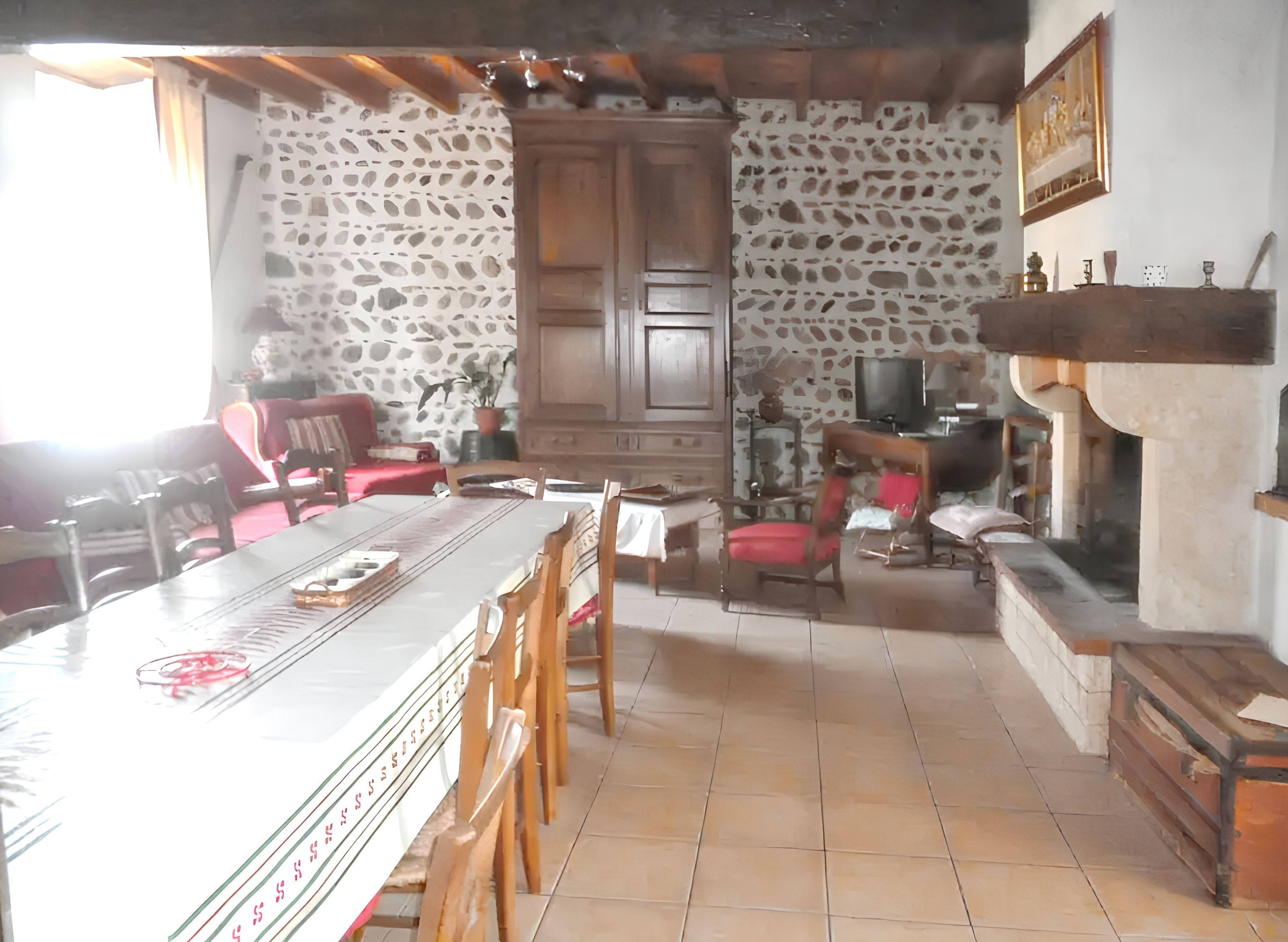 Un comedor con pared de piedra, mobiliario de madera y chimenea.