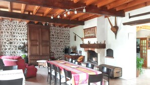 A dining area with a long table, chairs, a stone wall, and a fireplace. - Homerez - House in Bernac-Dessus (Bernac-Dessus)