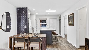 A modern kitchen with a central island, white walls, and a dining area with a wooden table and chairs. - Can't Beat Location! Enjoy the Balcony, Close to Gondola & Town Park (Telluride)