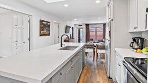 A modern kitchen with a large island, white cabinetry, and a dining area with a view. - Can't Beat Location! Enjoy the Balcony, Close to Gondola & Town Park (Telluride)