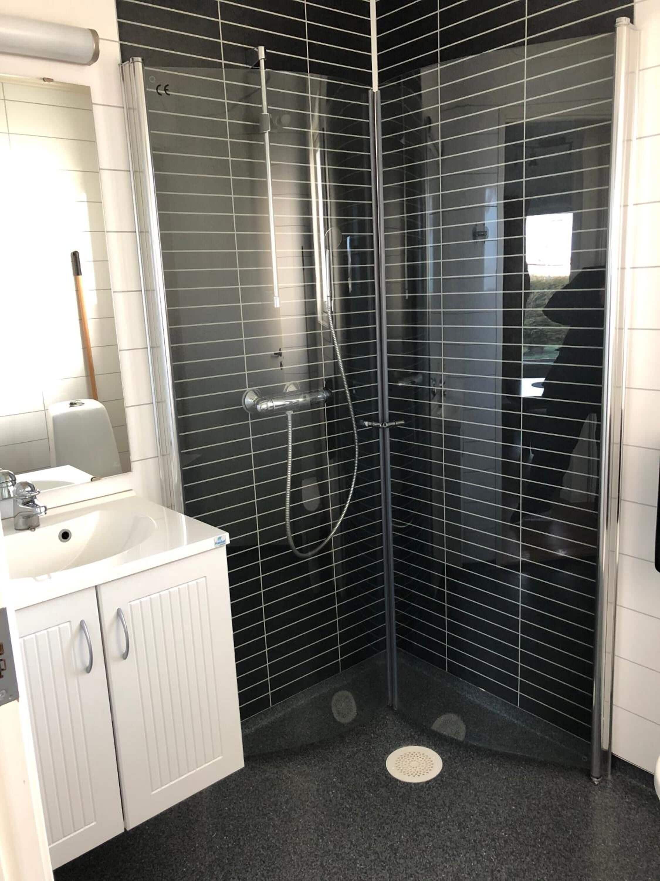 A modern bathroom with a glass-enclosed shower, white cabinetry, and a sink with a soap dispenser.