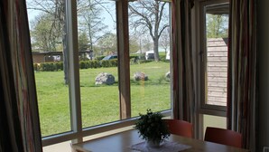 A dining area with a table and chairs, a potted plant, and a view of a grassy yard with rocks and trees. - Aktivitetsbyen Gamle Fredrikstad (Fredrikstad)