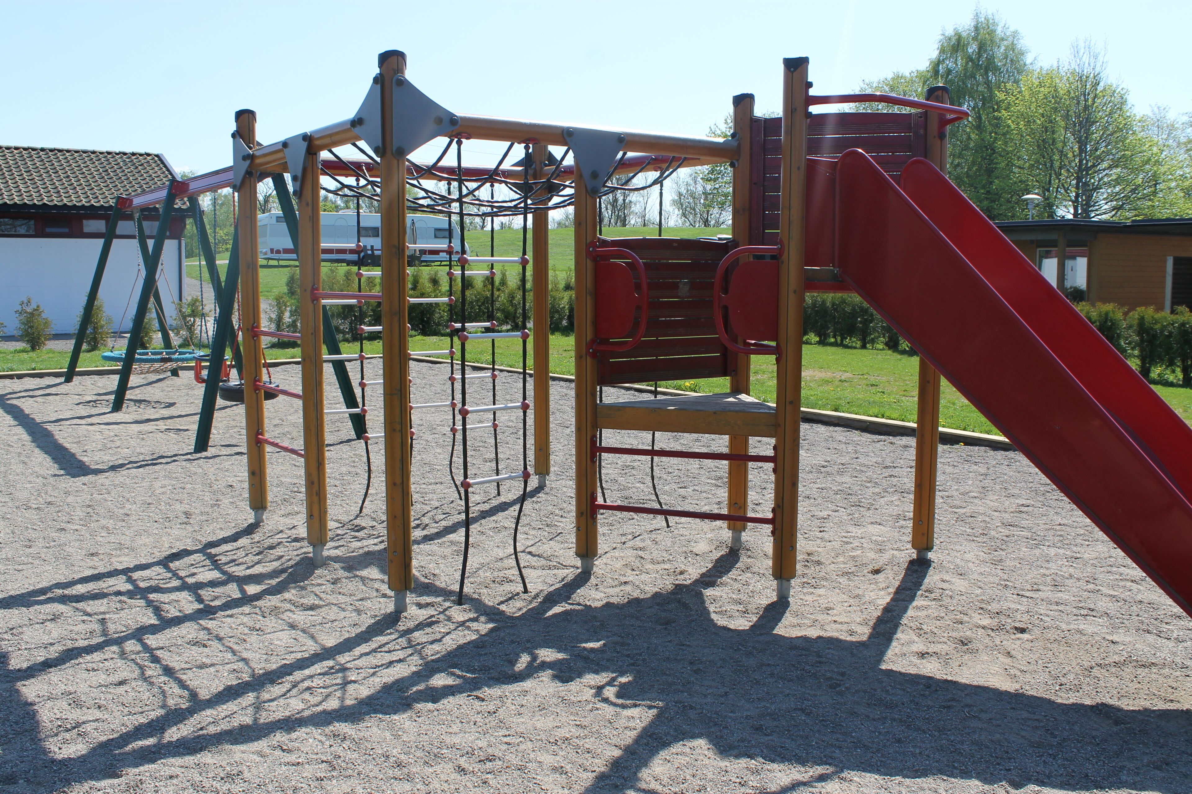 Un parque infantil con tobogán, estructuras para escalar y columpios.