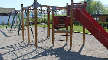 Un parque infantil con tobogán, estructuras para escalar y columpios.