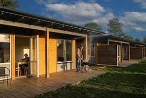 Un espacio exterior moderno con terraza de madera, una parrilla y una mesa de comedor con sillas.