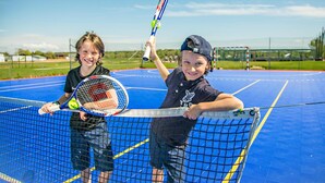 Two children playing tennis on a blue court with a net. - Aktivitetsbyen Gamle Fredrikstad (Fredrikstad)