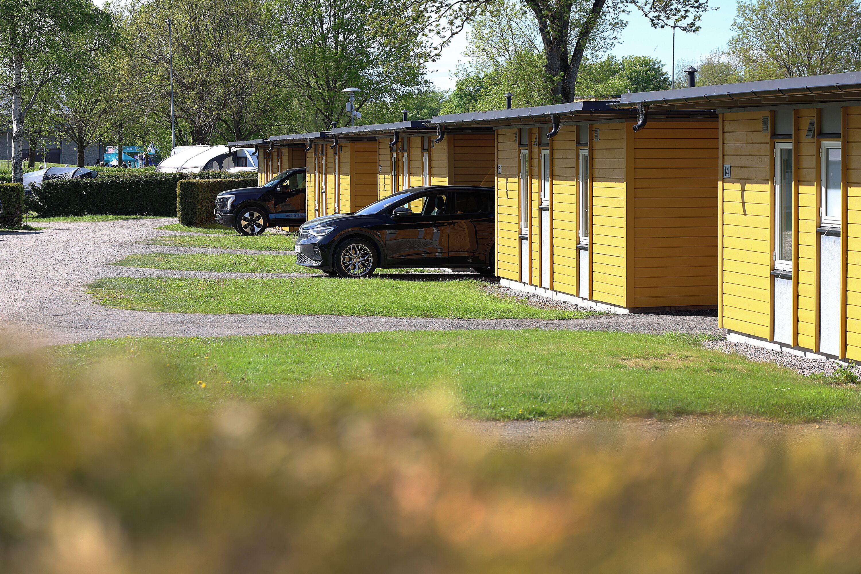 Une rangée de bâtiments jaunes d’un seul étage, avec un chemin de gravier menant à un espace de stationnement.