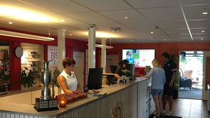 A hotel reception area with a counter, a clock, and a banner. - Aktivitetsbyen Gamle Fredrikstad (Fredrikstad)