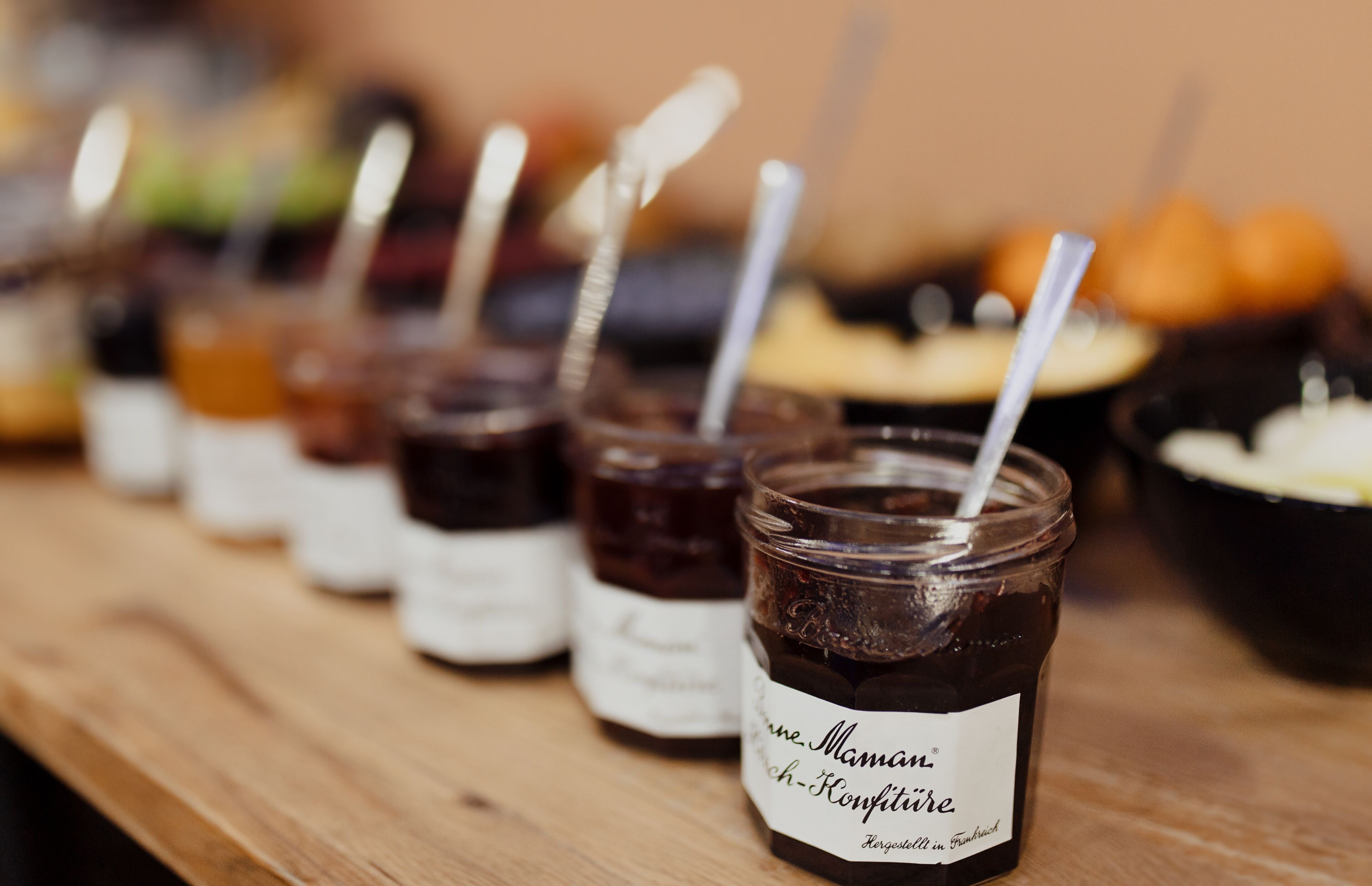 A row of jars with labels on a wooden surface.