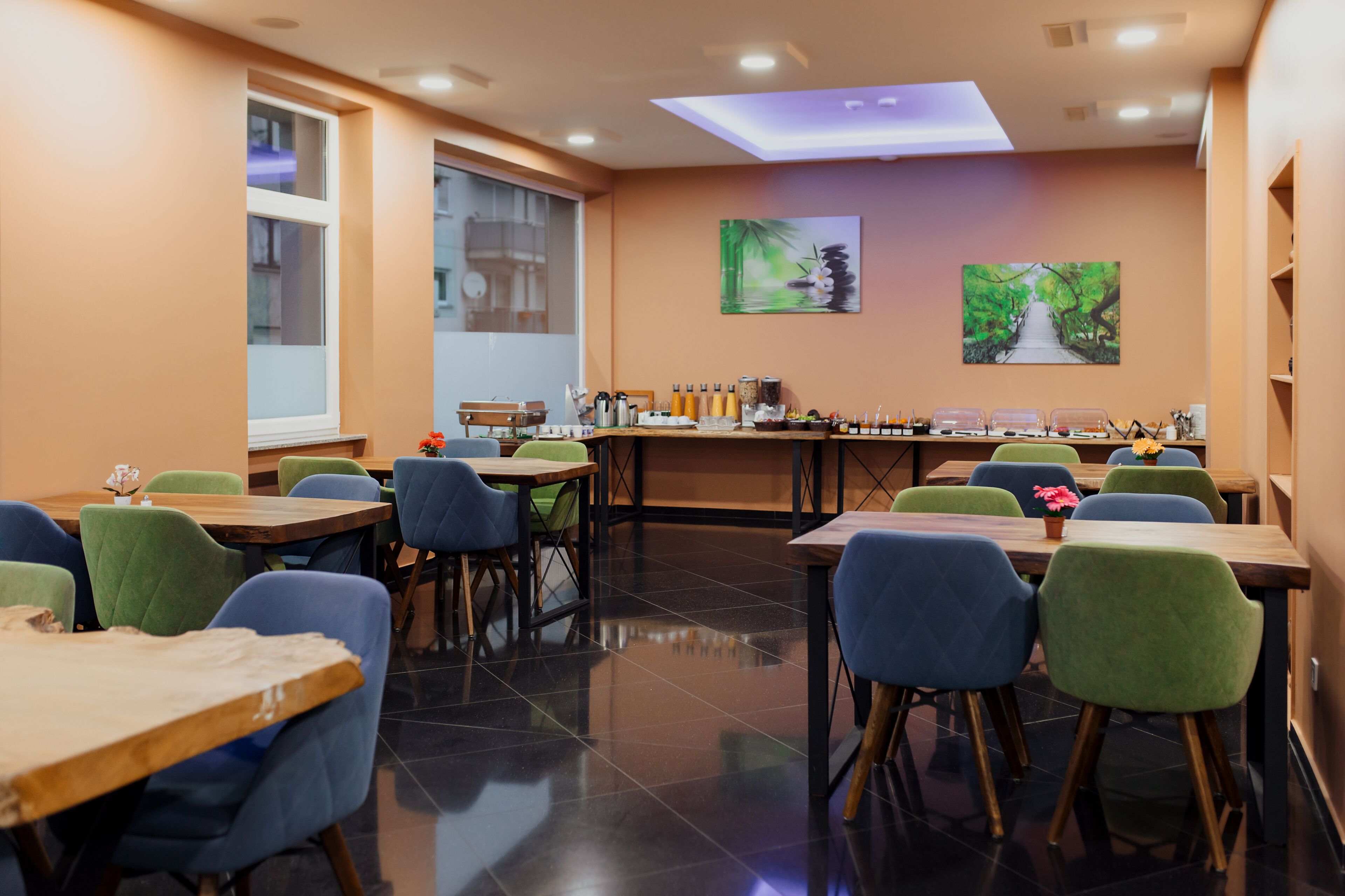 A dining area with tables and chairs, a counter with various items, and artwork on the walls.