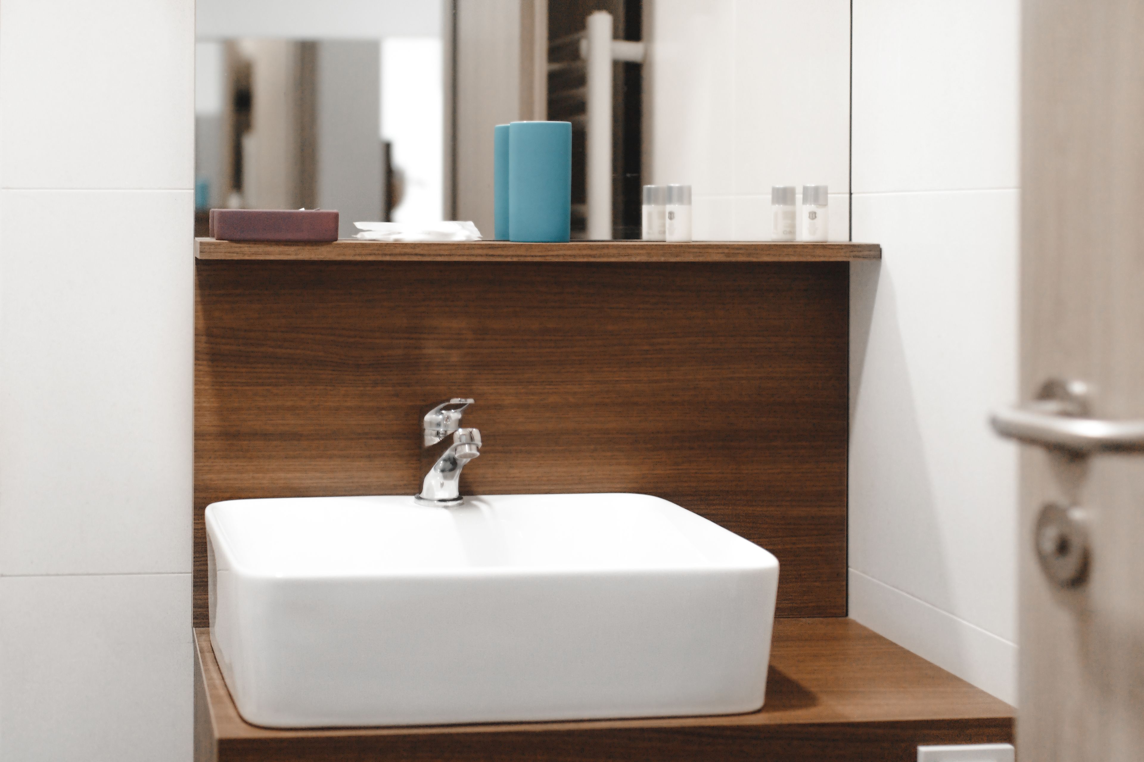 A bathroom with a white sink, wooden vanity, and a mirror.