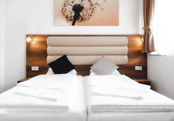 A double bed with white linens, a wooden headboard, and a wall-mounted artwork of a dandelion. - Hotel Castle Rastatt (Rastatt)