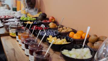 A buffet table with various fruits, cheeses, and jams.
