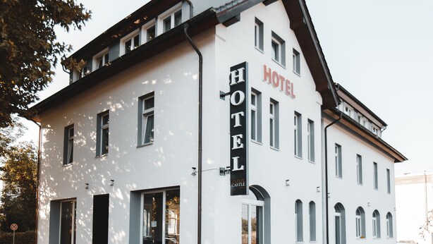 Un hotel de dos pisos con un llamativo letrero 'HOTEL' en la fachada, ventanas amplias y un diseño arquitectónico simétrico.